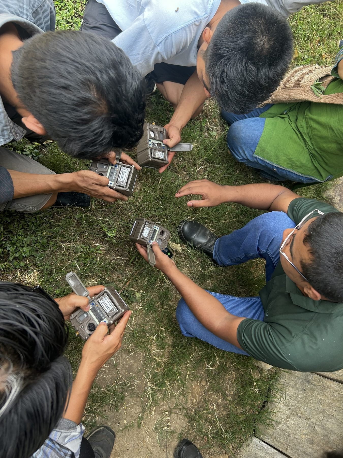 A group seated in a circle handling camera traps during a training session