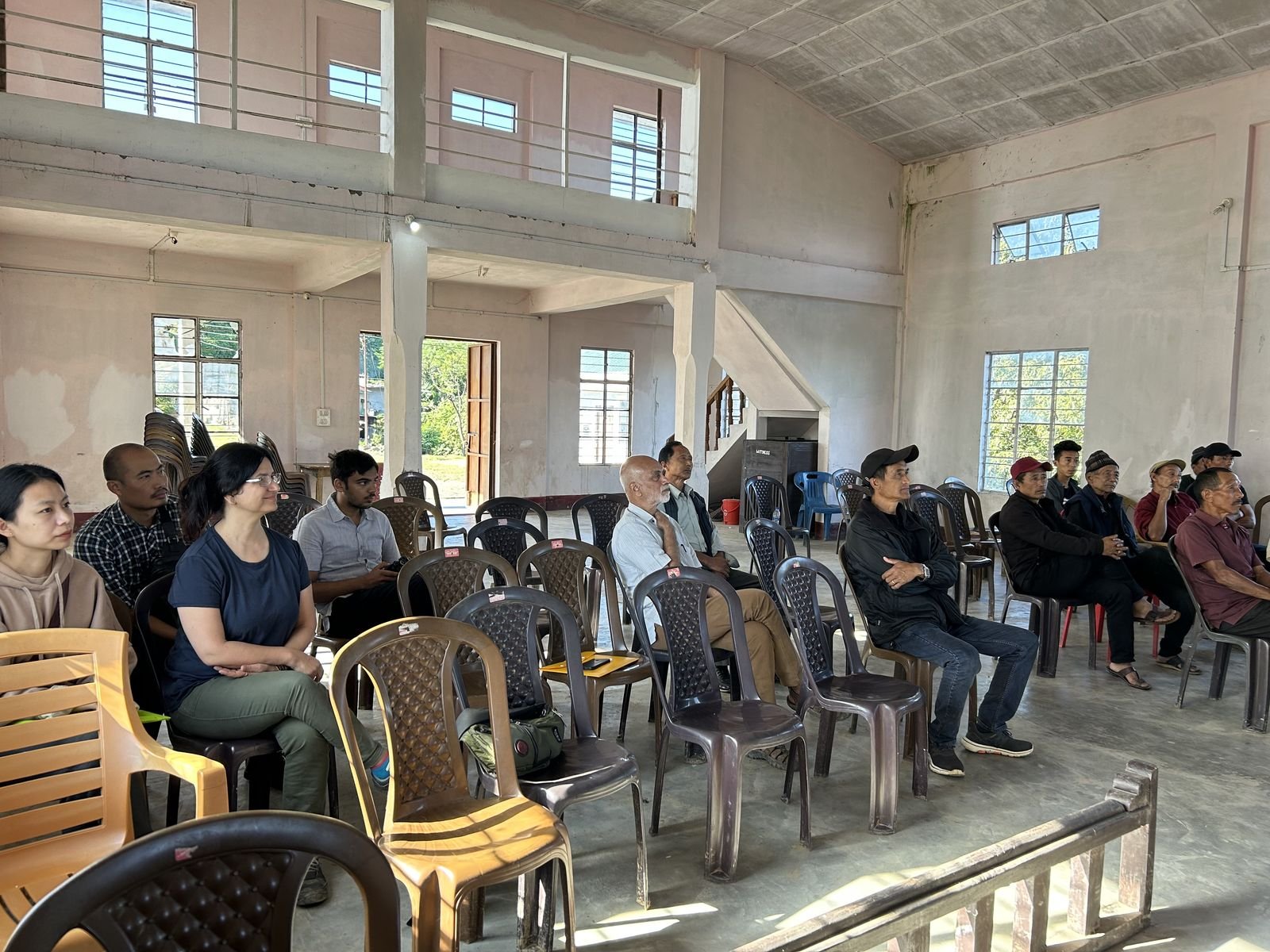 Village members seated at a community meeting in a hall