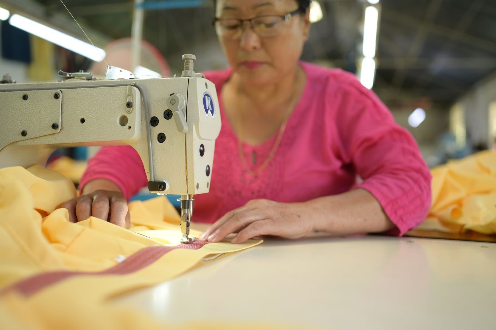 An operator stitching a striped seam on yellow fabric