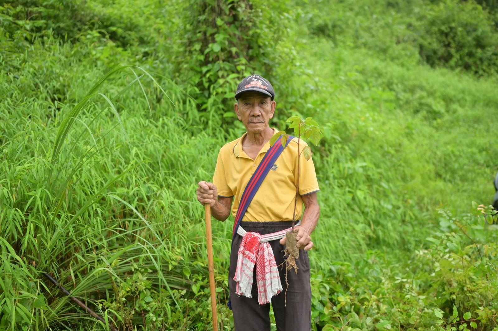 A Naga elder standing in tall grass on a hillside