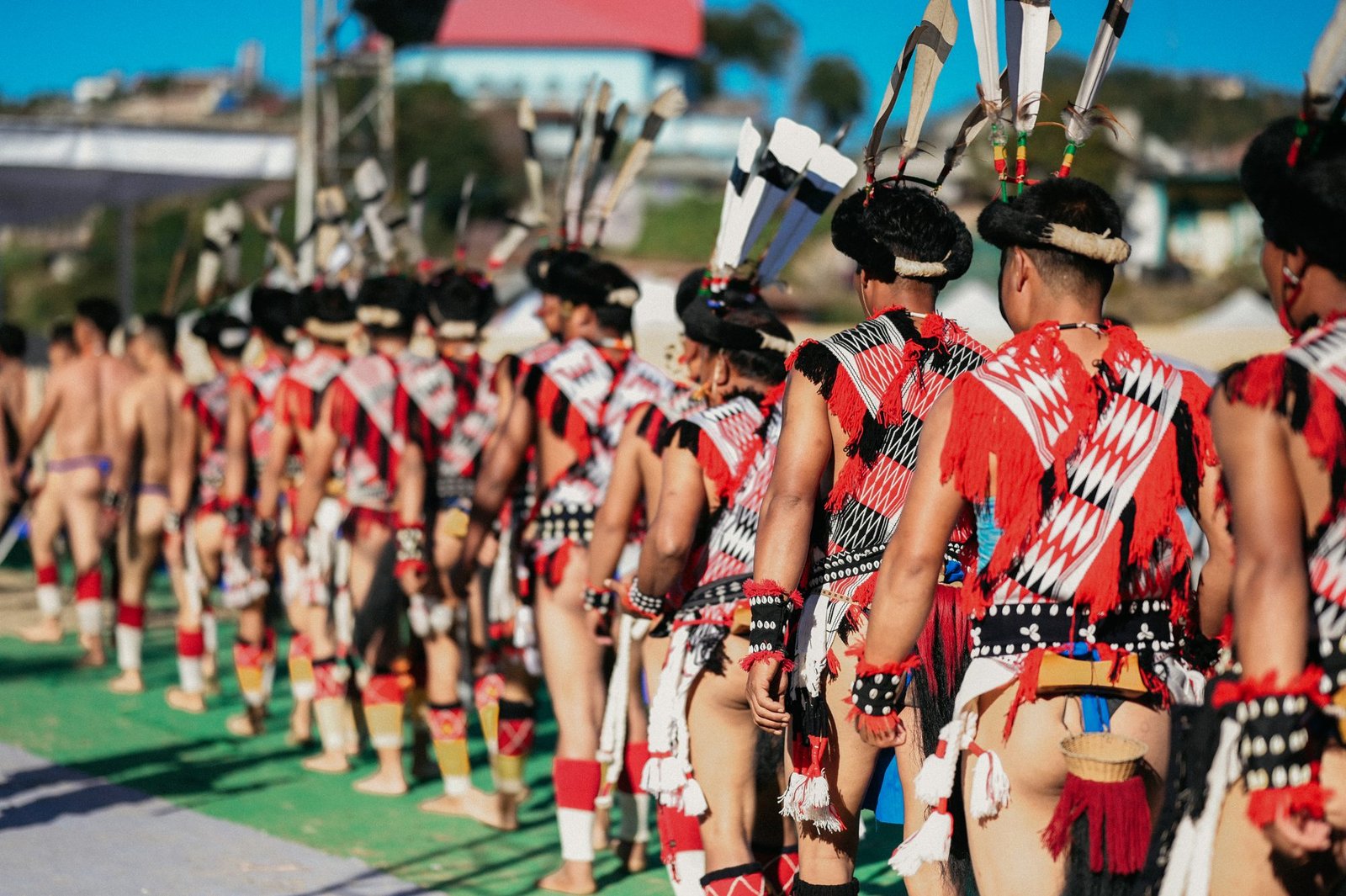 Rengma men in traditional dress and feathered headgear walking in procession at a festival ground