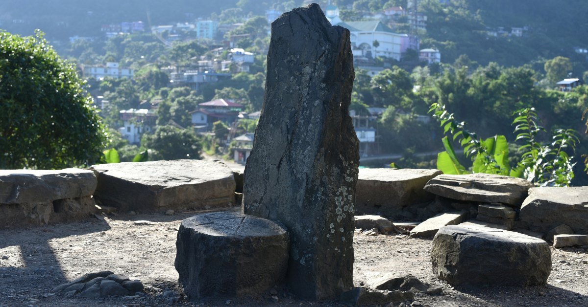 A standing stone and stone seats at a Binjwen resting place above Tseminyu town