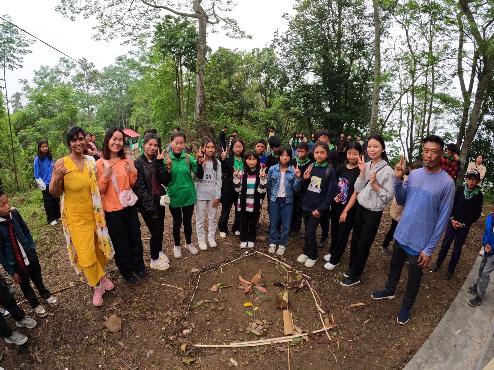 Children and facilitators around a mandala of leaves, stones, and bamboo