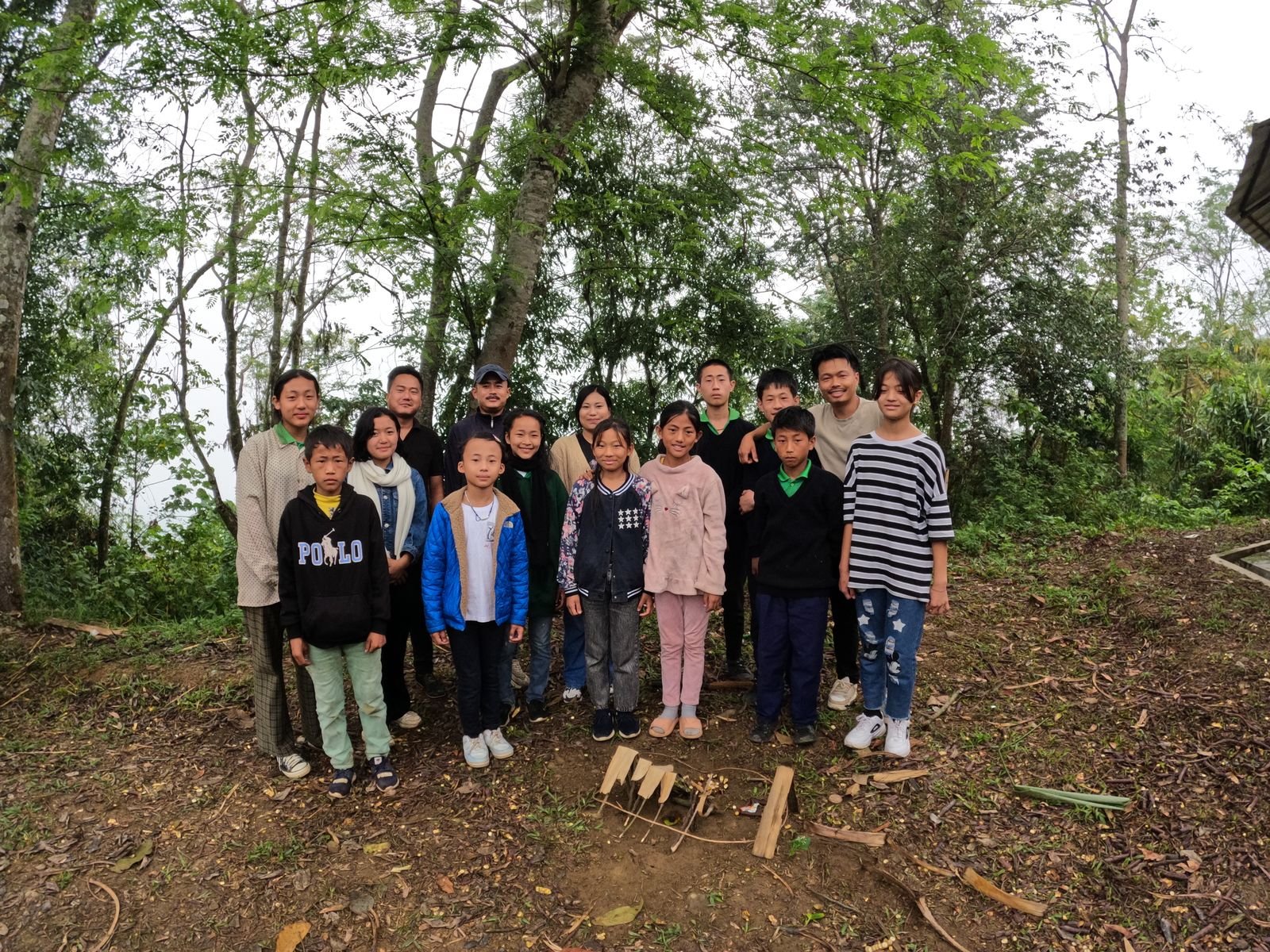 A group of children and facilitators with a model built from bamboo and sticks